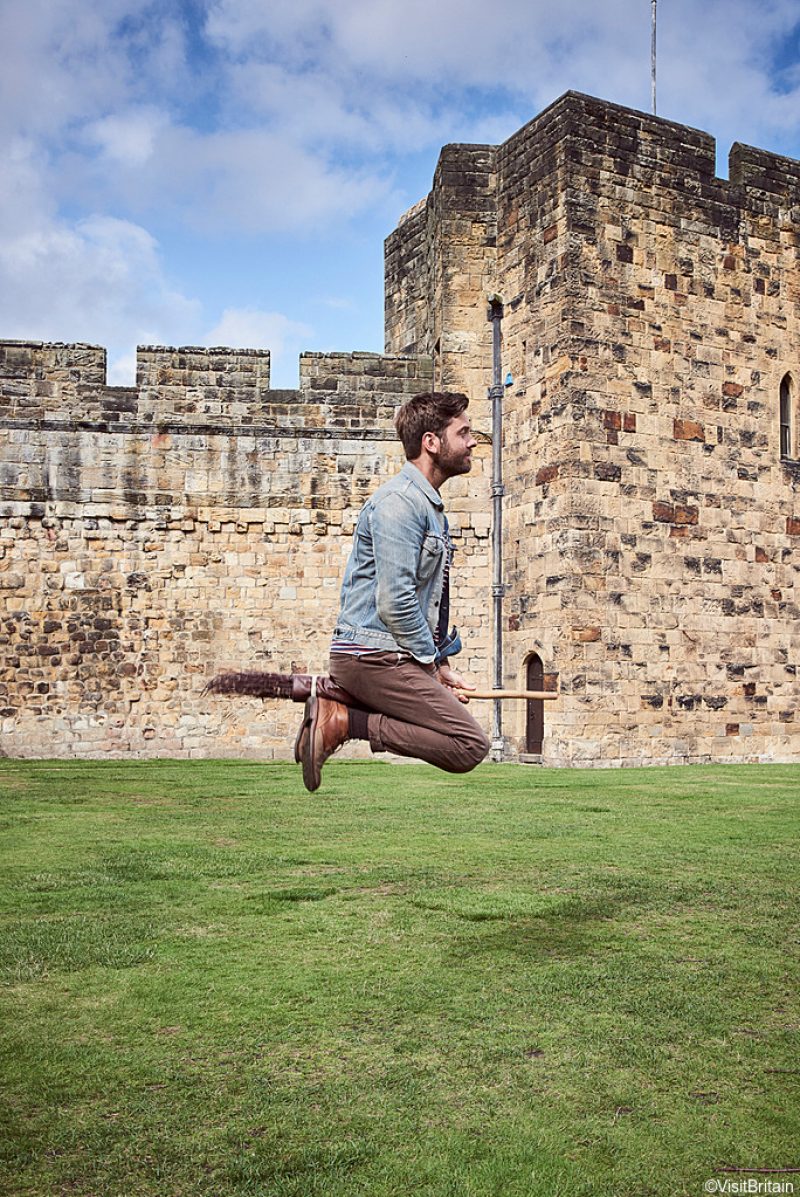 ©VisitBritain - Man hovering on broomstick in the Outer Bailey of Alnwick Castle, Northumberland