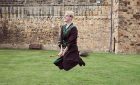 ©VisitBritain - Young man wearing robe and glasses hovering on broomstick in the Outer Bailey of Alnwick Castle, Northumberland
